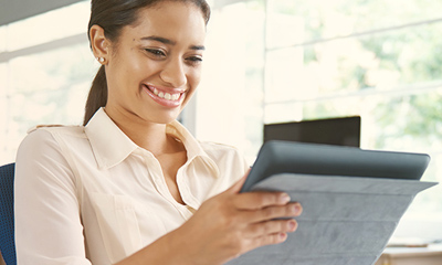 Women in business attire smiling looking at a tablet