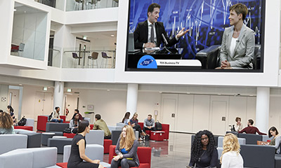Group of people in lobby with projected screen showcasing a program Group of people in lobby with projected screen showcasing a program